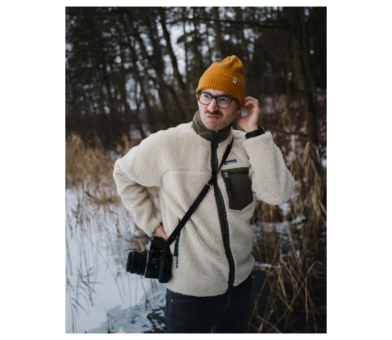 Portret Bartka Murackiego z aparatem i pięknym, długim wąsem na tle zimowego lasu